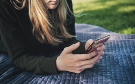 woman holding a cell phone at the park
